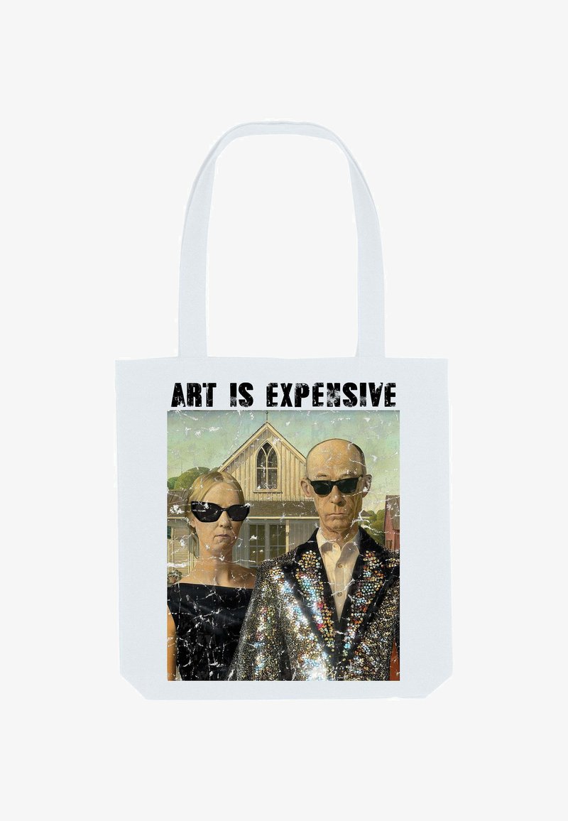 Twee personen met zwarte zonnebrillen en formele kleding staan voor een boerderij met de tekst "KUNST IS DUUR" boven hen.