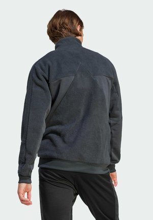 Pullover in pile scuro con collo alto, caratterizzato da un design a pannelli a contrasto. Tessuto morbido, vestibilità comoda e polsini e orlo a coste.