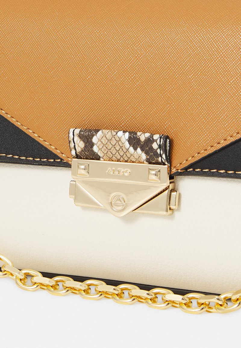 Sac à main marron, noir et blanc avec une finition texturée, présentant un rabat en imprimé serpent et des accessoires en métal doré avec une bandoulière en chaîne.