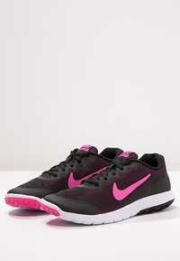 Černé síťované sportovní boty s růžovými akcenty, které mají texturovaný svršek, polstrovanou podrážku a charakteristický vzor Chevron na podrážce.