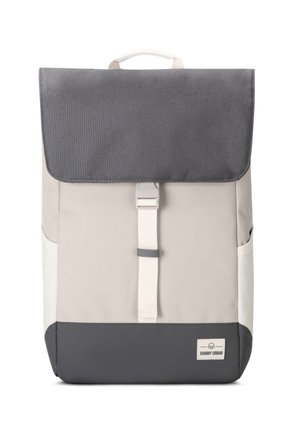 Sac à dos dans des tons beige et gris, avec une fermeture à rabat, une sangle blanche et une petite étiquette de logo en bas. Matériau texturé et forme structurée.