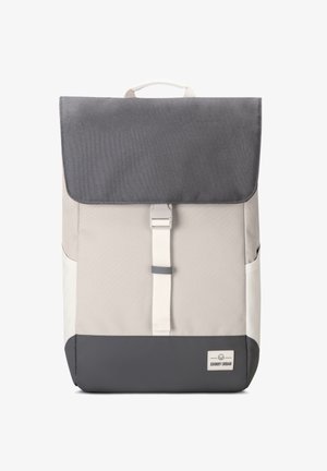 Beige en grijze rugzak met een klep-sluiting, witte schouderband en een klein logo-label aan de onderkant. Geweven materiaal en gestructureerde vorm.