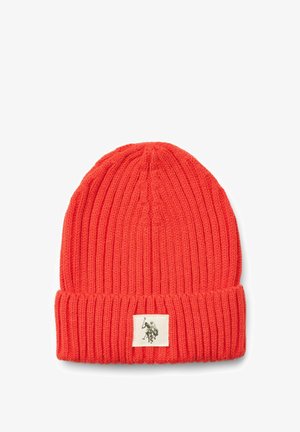 Piros kötött sapka bordás textúrával és felhajtott szegéllyel. Egy kis szövet címke található rajta, kontrasztos színű grafikai mintával.