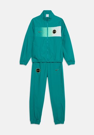 Ensemble de survêtement Nike vert sarcelle avec veste et pantalon, avec une bande horizontale vert clair et blanche et des logos dorés sur la poitrine et la cuisse.