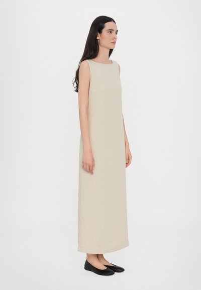 Beige liinus maxi mekko, jossa on neliökaula-aukko ja hihaton muotoilu. Yhdistetty mustien tasapohjaisten kenkien kanssa. Yksinkertainen, suora siluetti.