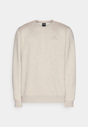 Hellbeiges Sweatshirt aus weichem Material, mit Rundhalsausschnitt, langen Ärmeln und einem kleinen Logo auf der Brust.