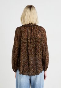 Kergesti läbipaistev lillemustriga pluus pikade puhv-sleeve'idega. Tume taust punaste, kollaste ja siniste lillede kogumitega. Kõrge kaelus.