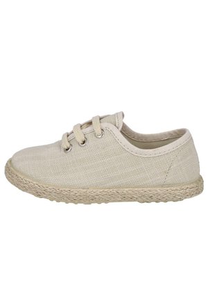 Zapatilla de lona beige para niño pequeño con tres ojales, cordones beige y suela con textura tejida.