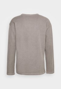 Grå ribbad långärmad topp med rund halsringning, som har en avslappnad passform och mjuk textur. Baksidan är enfärgad utan ytterligare detaljer.