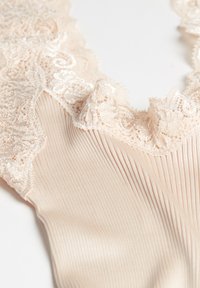 Mjukt beige bodysuit med vertikala ribbor, som har en scalloped spetskrage och trim. Spetsen har intrikata blommönster längs kanten.