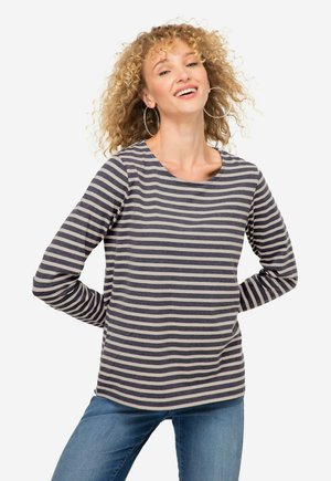 Chemise rayée à manches longues en bleu marine et beige. Mélange de coton doux avec un col rond et un ourlet arrondi. Portée avec un jean bleu clair.