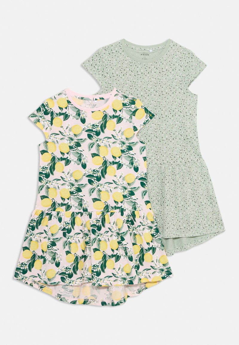 Dwie sukienki: jedna z nadrukiem cytryn i liści na różowym tle, druga w kolorze zielonym z małym białym wzorem kwiatowym. Obie mają krótkie rękawy.