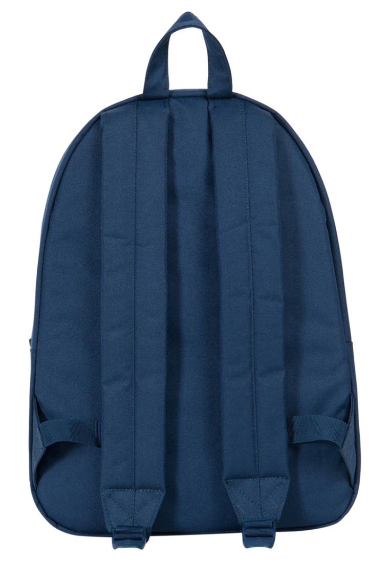 Sac à dos en tissu bleu marine avec des bretelles rembourrées et une poignée supérieure. Texture lisse, forme arrondie et design minimaliste.