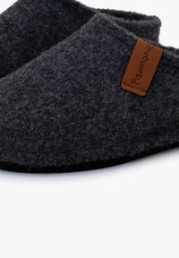 Pantofole grigie in feltro con una forma arrotondata, una texture morbida e una toppa in pelle marrone con il nome del marchio.