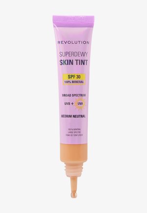 Revolution Superdewy Skin Tint in een paarse tube met een beige dop. Het etiket vermeldt SPF 30, 100% mineraal en een medium neutrale tint.