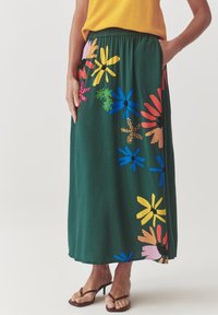 Fustă maxi verde cu imprimeu floral, având un talie elastică strânsă. Prezentă imprimeuri florale multicolore, buzunare și o textură netedă, moale.