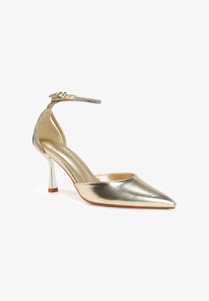 Scarpa con tacco alto in metallo dorato con punta a punta, cinturino alla caviglia adornato con piccoli strass e tacco sottile e curvo.