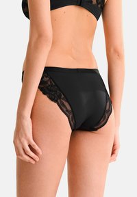Culotte en dentelle noire avec motif floral sur les côtés, en tissu lisse, design taille haute, dotée d'une taille et d'un dos sans couture.