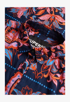 Camicia blu navy con motivi floreali in rosso, rosa e blu, colletto con bottoni e etichetta "Superdry". Tessuto morbido e strutturato.