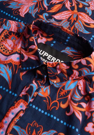 Korte mouwen shirt met een marineblauwe achtergrond en levendige bloemenpatronen in oranje, roze en blauw. Voorzien van een button-down kraag en label.