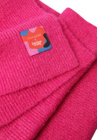 Tessuto lavorato a maglia rosa con una texture a coste, caratterizzato da un'etichetta cucita in rosso, blu e nero con un design astratto e del testo.