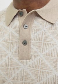 Beige polo tričko s texturovaným geometrickým vzorem, se límečkem a třemi šedými knoflíky.