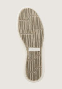 Sohle eines Sneakers mit einer strukturierten beigefarbenen Gummibasis und wellenförmigen Mustern, beschriftet mit "TOM TAILOR" und der Größe "33" in einem rechteckigen Feld.