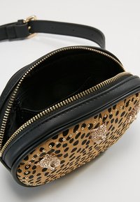 Okrągła torba na ramię z czarną skórzaną górą i panterkowym dołem, ozdobiona złotymi ćwiekami i metalicznymi akcentami. Zapięcie na suwak.