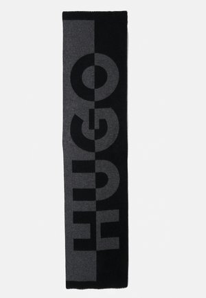 Sort og grå tørklæde med stort "HUGO" logo. Lavet af blødt, struktureret materiale med kontrasterende farveblokke og fed typografi.