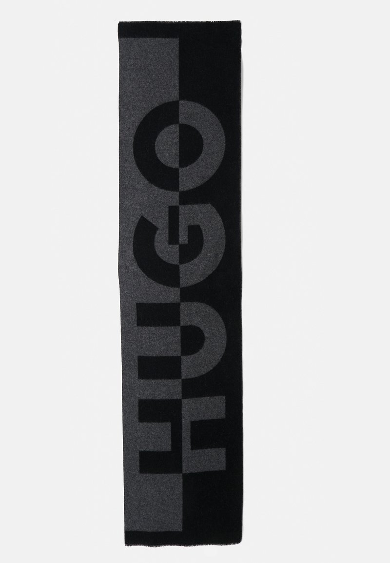 Must mustriba mustriba, mille suur HUGO logo. Valmistatud pehmest, tekstuurilisest materjalist, kontrastsete värviblokkide ja julge typograafiaga.