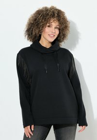 Sudadera negra con cuello alto y corte relajado. Cuenta con detalles de flecos en las mangas y cordones en el escote. Material de mezcla de algodón.