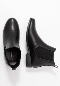 Stivaletti neri alla caviglia realizzati in pelle liscia e tessuto elastico, con punta arrotondata e piccolo tacco a blocco, con dettagli traforati.