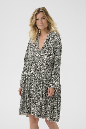 Langarm jurk in zwart-wit zebra print, met een V-hals, geplooide gelaagde rok en zachte stofstructuur.