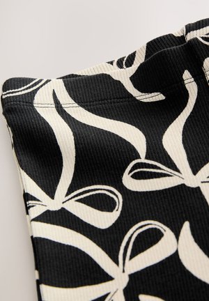 Mustast soonikangast, millel on valged kikilipsud. Näidatud nurga alt, rõhutades tekstuuri ja õmbluse detaile.