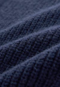Marineblauer Strickstoff mit strukturierten Rillen, der eine weiche, flauschige Oberfläche und ein gleichmäßiges Webmuster aufweist.