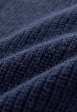 Marineblåt strikket stof med teksturerede riller, der viser en blød, fluffy overflade og et ensartet vævemønster gennem hele materialet.