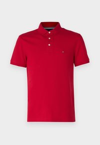 Polo rouge à manches courtes avec trois boutons et un petit logo rectangulaire sur la poitrine gauche.