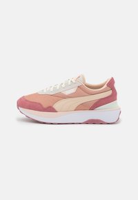 Rosa och beige Puma-sneakers med vita snören, nät- och mockadetaljer, samt tjock vit sula på neutral bakgrund.