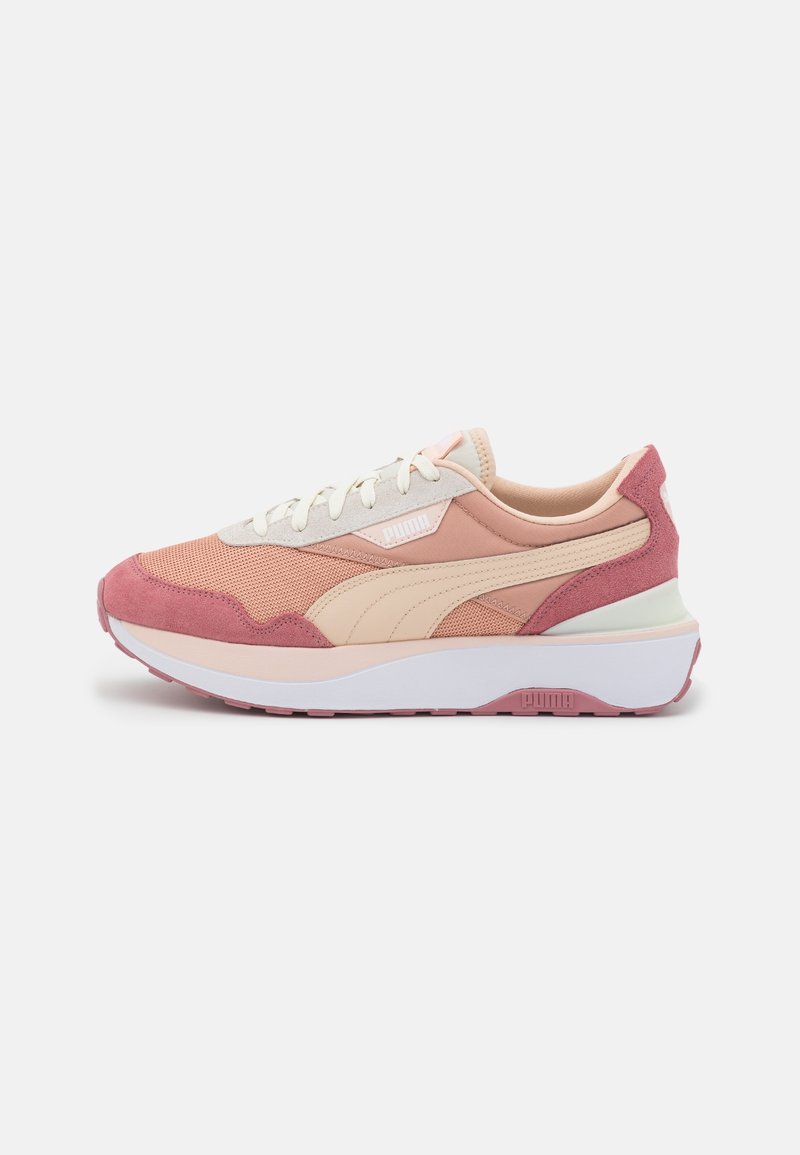 Rosa och beige Puma-sneakers med vita snören, nät- och mockadetaljer, samt tjock vit sula på neutral bakgrund.