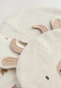 Encantador artículo de tela beige con características de animal, textura suave, detalles bordados y acentos marrón claro, incluyendo orejas y rostro.