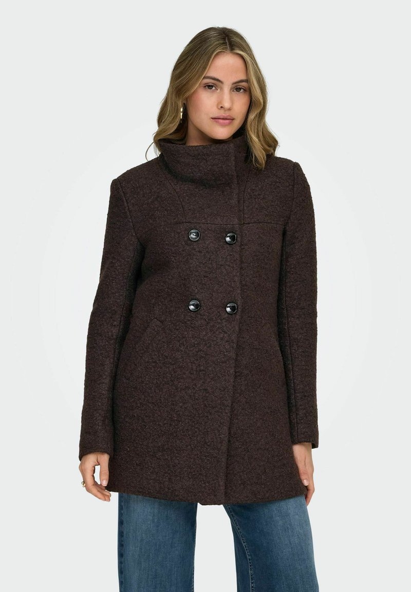 Pruun kahekordne mantel kõrge kraega, valmistatud tekstureeritud kangast, mustade nööpide ja küljetaskutega.