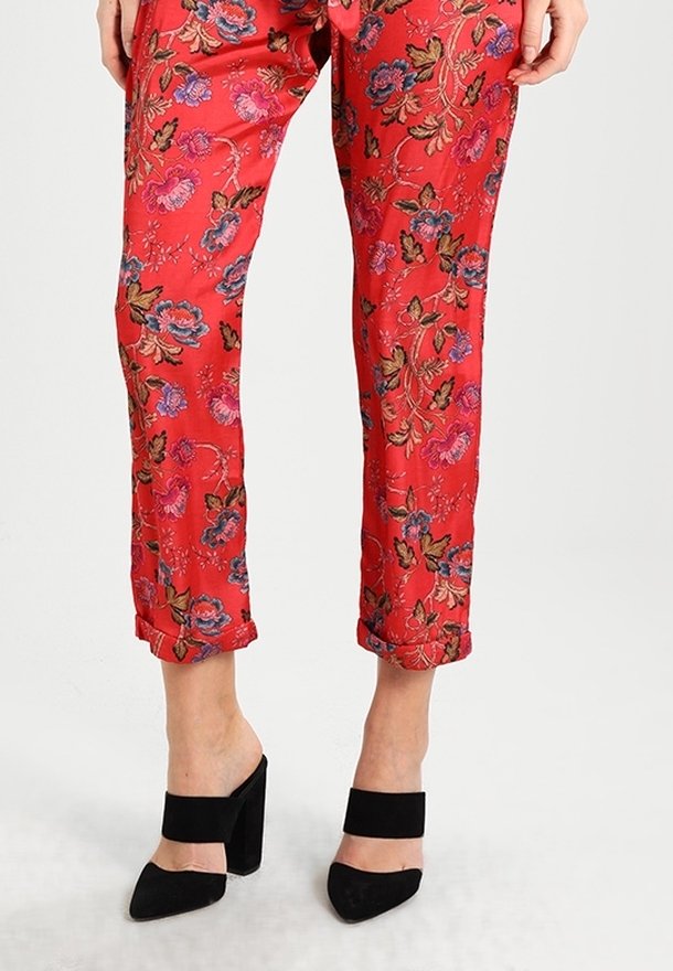 Röda blommiga byxor i slätt tyg, med uppvikt fåll och intrikata rosa och blå blommönster. Matchas med svarta klackskor med blockklack.