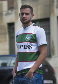 Groen en wit gestreept shirt met rode accenten, voorzien van het 'GUINNESS' logo, ronde kraag, gedragen met blauwe denim jeans.