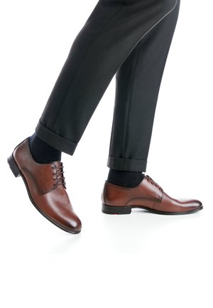 Bruine leren nette schoenen met een gladde afwerking, vetersluiting, ronde neus en een contrasterende zwarte zool, gecombineerd met donkere, omslag schoenen.