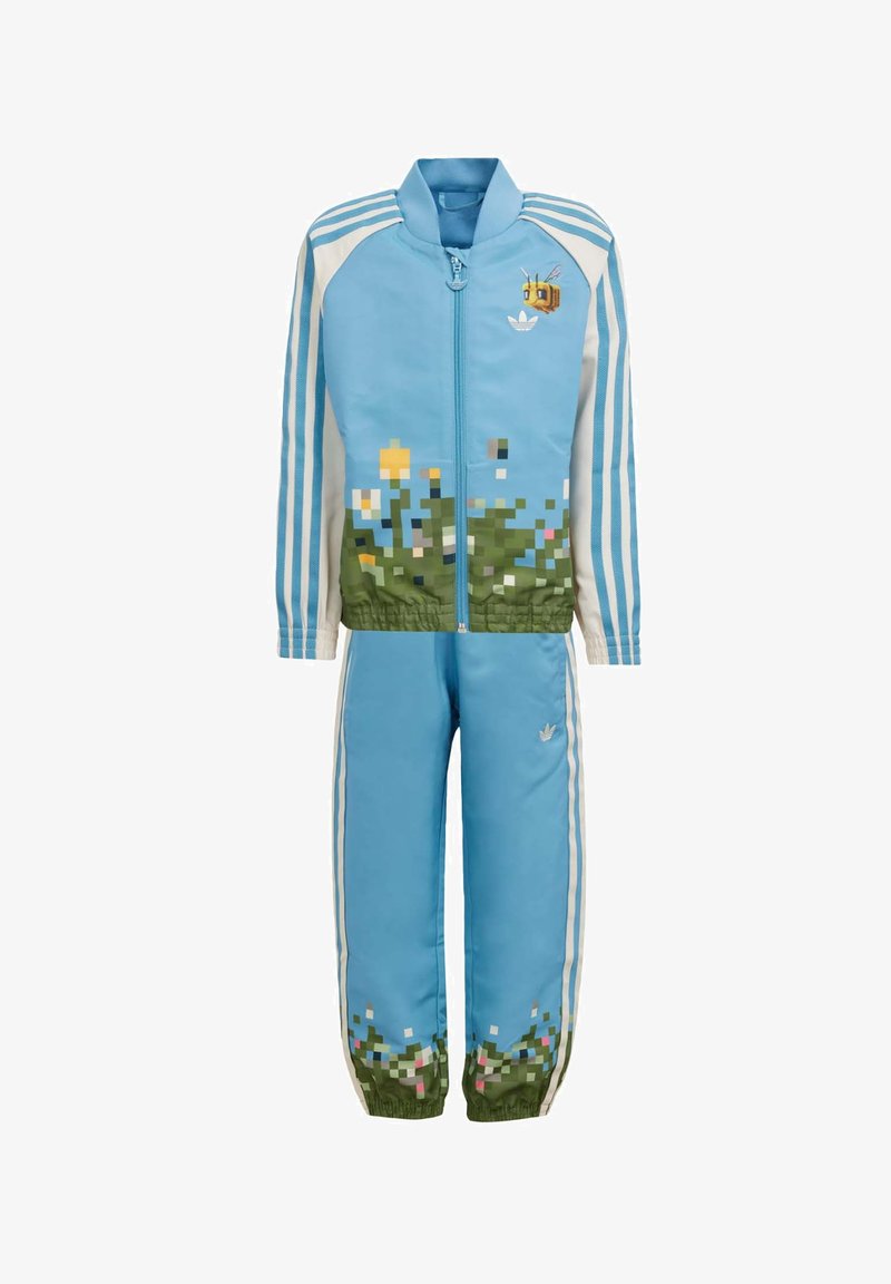 Modrý tréningový súbor s kvetinovým pixelovým vzorom na spodnej časti; zipsová bunda so tromi bielymi pruhmi a detailom včely na hrudi; nohavice s elastickým pásom.