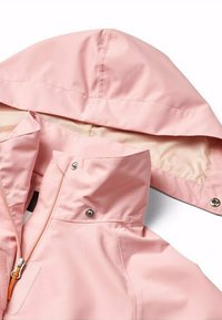 Giacca impermeabile di colore rosa chiaro con cappuccio, chiusura con zip e tirante arancione, e fodera interna liscia. Tessuto resistente con bottoni a pressione.
