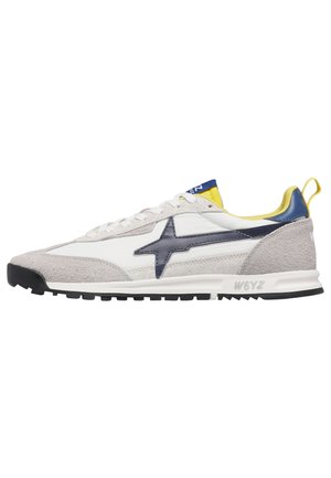 Baskets en daim blanc et gris avec un logo étoile bleu marine, une doublure intérieure jaune et bleue, et une semelle noire crantée.