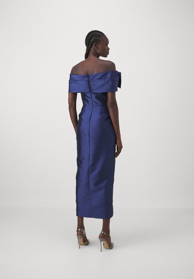 Off-the-shoulder, satin evening dress in dark blue. Fitted design with a straight silhouette and visible zipper at the back. Heels add elegance.