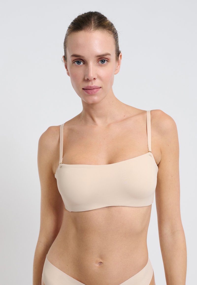 Nude bandażowy biustonosz z cienkimi regulowanymi ramiączkami, bezszwowy design, gładka faktura i minimalne detale hardware. Prosty i funkcjonalny.