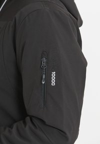 Svart vattentät jacka med en dragkedja på ärmen och texten "W-PRO 10000" präglad, med en slät, matt yta.